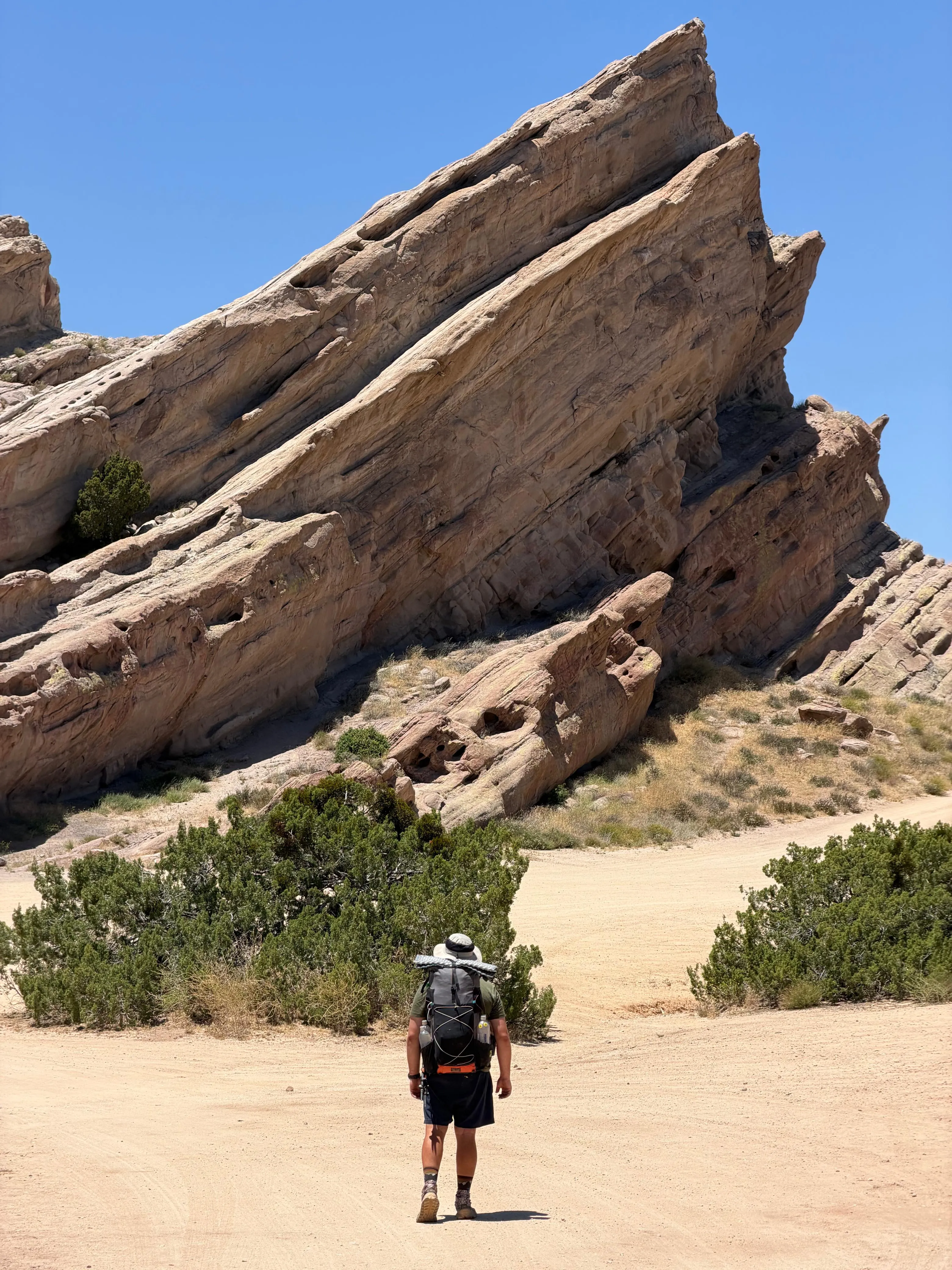 Neil hiking towards huge tilted sandstone slabs in the Southern California desert