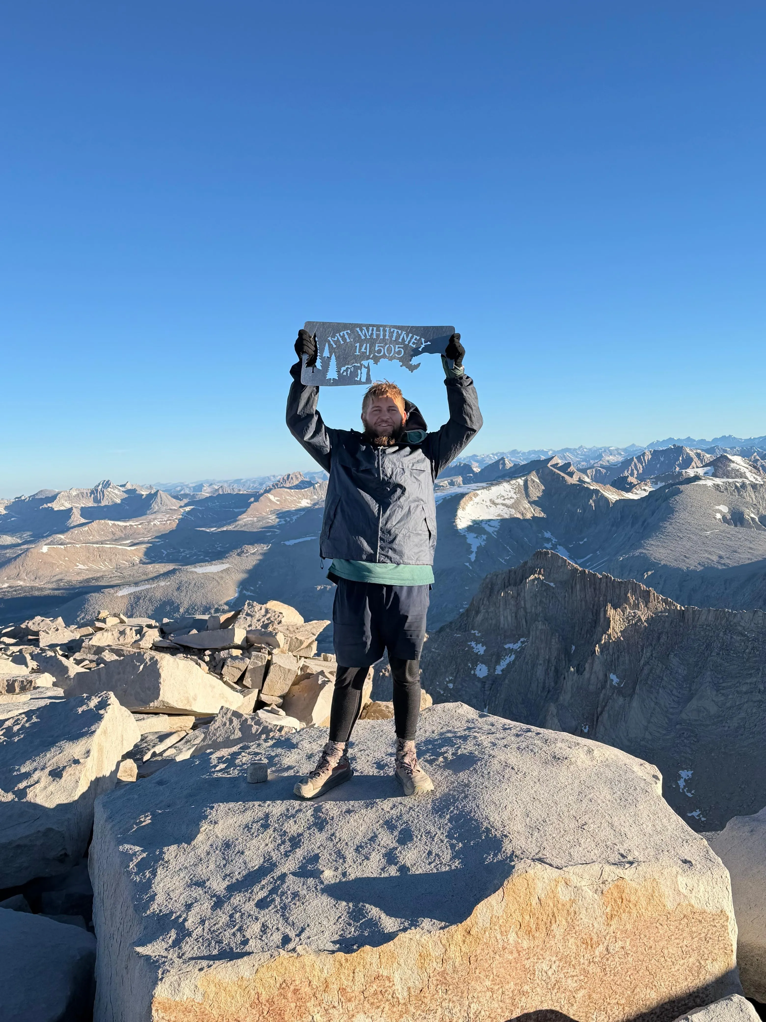 Neil on the summit of Mount Whitney, holding up the 14,505 ft summit sign