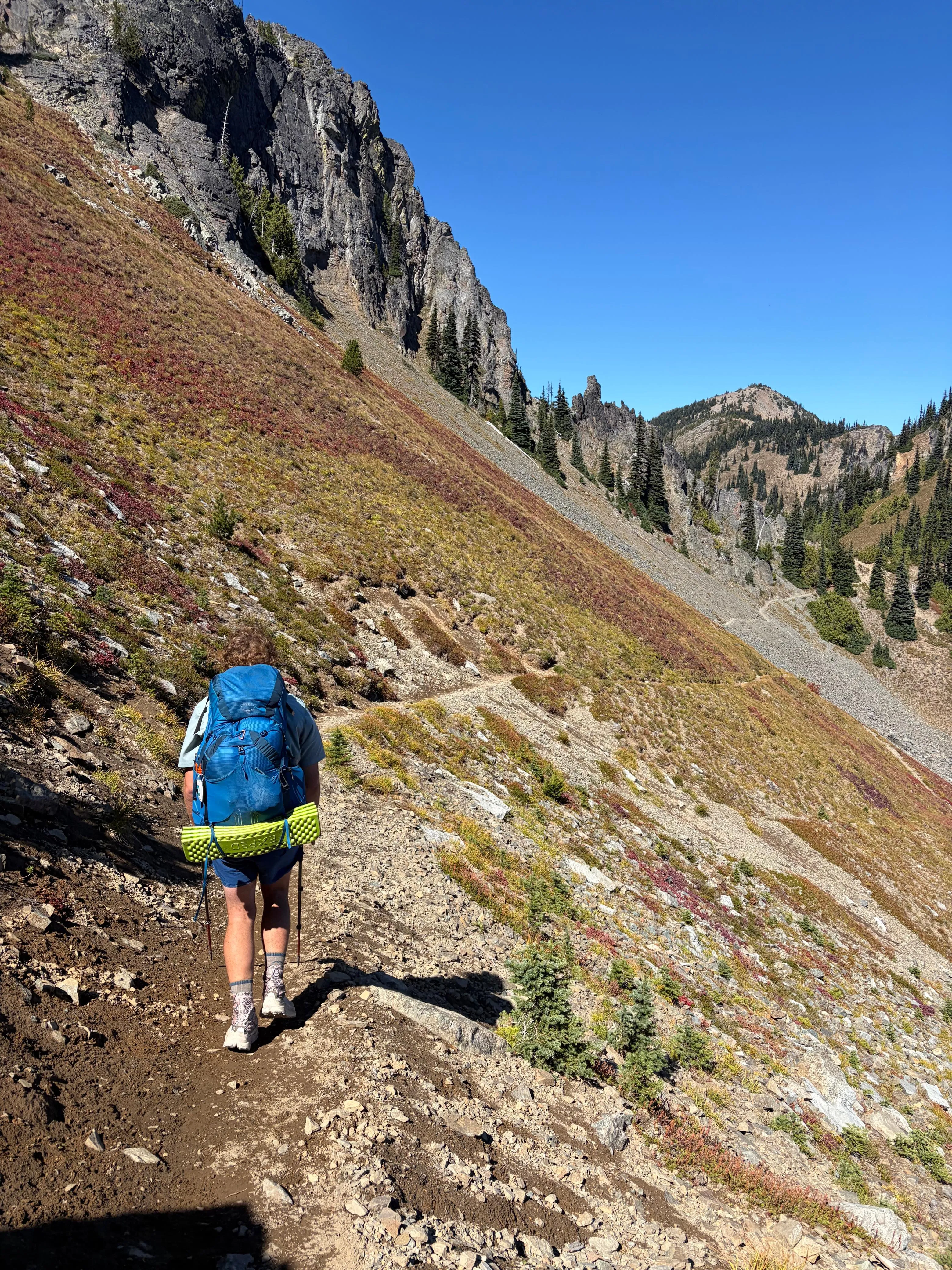 Neil's fiancée hiking a steep mountainside trail in Washington, the slope red and gold with autumn colours